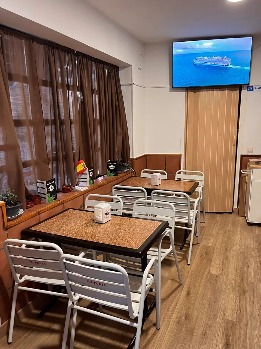Comedor interior de Casa Bianca, con las mesas preparadas y la televisión al fondo